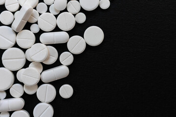 A lot of white pills on a black background.Copy space.