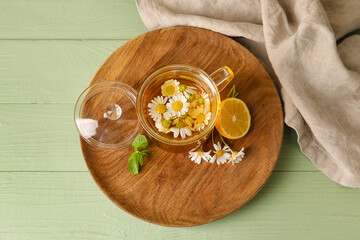 Composition with tasty chamomile tea on color wooden background