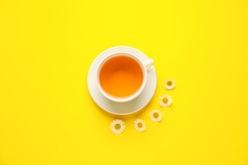 Cup of tasty chamomile tea with flowers on color background