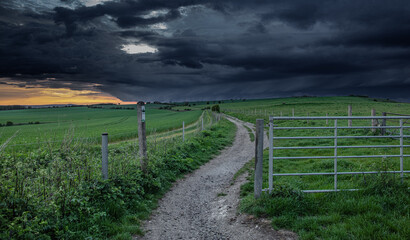 Dramatic cloudy sunset sky over a dirt road through the countryside