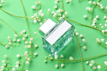 Bottle of perfume and lily-of-the-valley flowers on color background, closeup