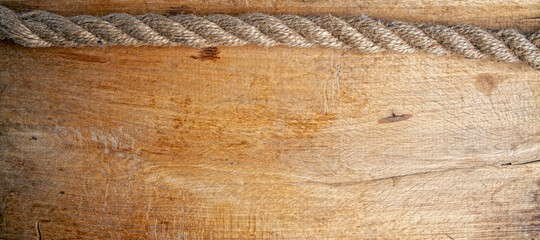 an old rough oak board and a nautical rope on it forming a frame with an empty space 