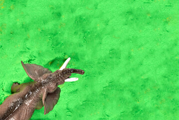 Toy elephant on green kinetic sand, children's games.