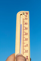 Natural lighting. a human hand holds a wooden thermometer. The temperature on it is very high. Heat.