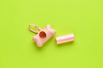 Dispenser with pet waste bags on color background