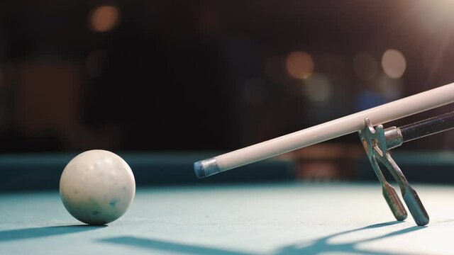 Male billiard player gets ready to stroke a ball with cue stick using rest