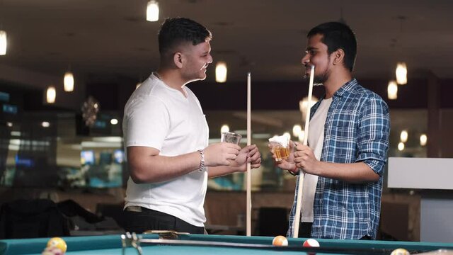 Two young handsome men playing in pool at bar