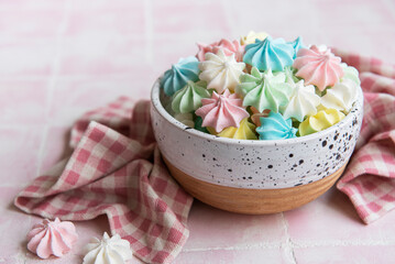 Fototapeta na wymiar Small colorful meringues in the ceramic bowl