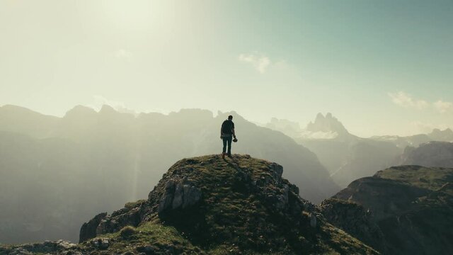 A male hiker on a hill in the mountains during sunrise. The Dolomites in South Tyrol. Slow panning footage.