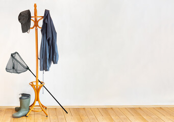 The equipment for fisherman hangs on the coat hook in a empty room with wooden floor.