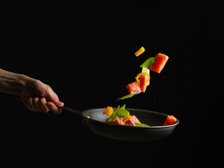 A beautiful still life of red fish, vegetables, herbs. Beautiful contrast - bright ingredients and black background. Levitation. Minimalism. Color image. High angle view.