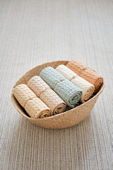 Collection of natural muslin bath towels in a wicker basket on the floor. Natural, soft, air and stylish home textiles. View from above.