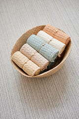 Collection of natural muslin bath towels in a wicker basket on the floor. Natural, soft, air and stylish home textiles. View from above.