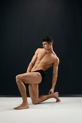sporty man with a pumped-up naked body posing on his knee