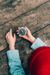 A women in red hat and blue coat holds a compass in hand and is guided by the area, autumn forest,...