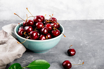 A bowl ripe cherries on a light gray background, summer berries on the table copy space for text