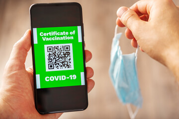 A man holds electronic certificate of vaccination covid 19 and a medical mask in his hands,qr code confirming the presence or antibody immunity