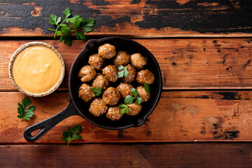 Traditional swedish meatballs in a fried pan with creamy sauce on old wooden table top view copy...