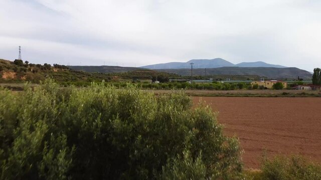 Dron going forward across the trees revealing Moncayo mountain with wind turbines