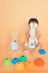 Obraz na płótnie Canvas A toddler playing Peek-A-boo with soft toys bunnies.