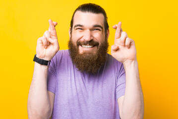 Young smiling bearded man crossing fingers for good luck, making a wish