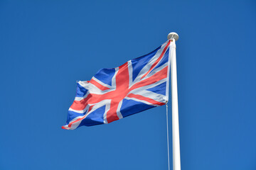 British Union Jack flag flying against a plain blue sky