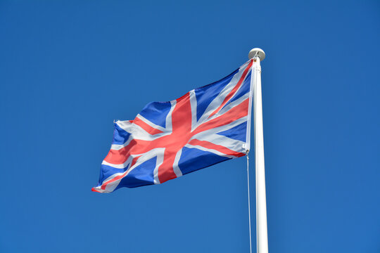 British Union Jack Flag Flying Against A Plain Blue Sky