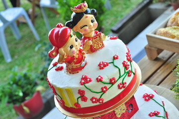A wedding cake decorated with a couple dressed in traditional Chinese wedding gowns