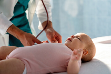 Obraz na płótnie Canvas Pediatrician doctor examines baby with stethoscope checking heart beat.