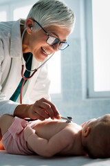 Pediatrician doctor examines baby with stethoscope checking heart beat.