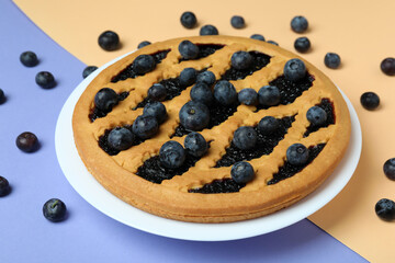 Delicious blueberry pie with berries on two tone background