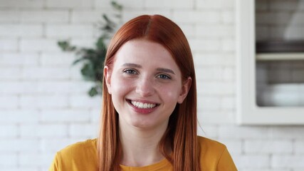 Portrait of a beautiful smiling red-haired girl looking at the camera