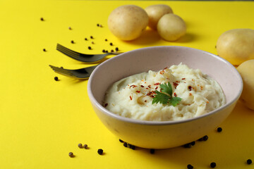 Plate of mashed potatoes and ingredients on yellow background
