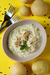 Plate of mashed potatoes and ingredients on yellow background
