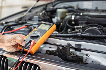 A technician is checking the car battery for availability.