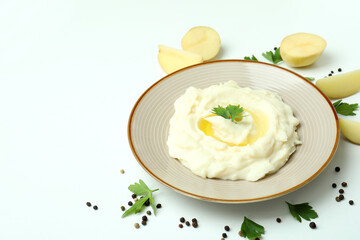 Plate of mashed potatoes and ingredients on white background