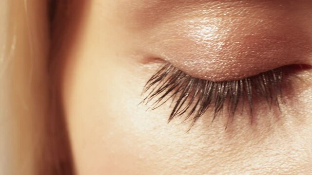 Eye health. Vision care. Eyesight ophthalmology. Macro of blonde woman gray brown iris pupil shimmering eyelid lashes on radiant face.