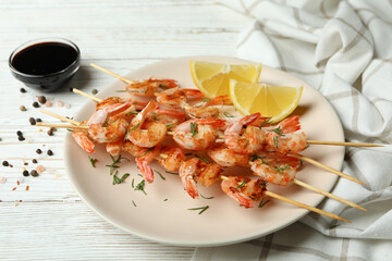 Plate with grilled shrimps on white wooden background