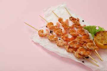 Tasty grilled shrimps skewers on pink background
