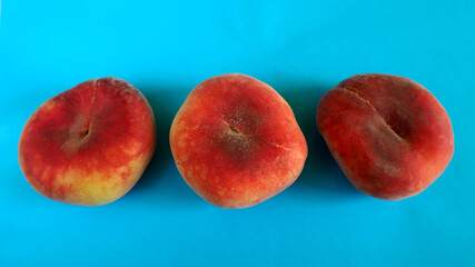 three pink fig peaches lie on a blue background top view