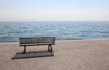 lonely bench on the shore with the placid water symbol of tranquility and relaxation
