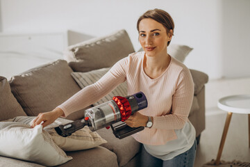 Young woman with rechargeable vacuum cleaner cleaning at home