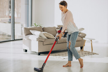 Young woman with rechargeable vacuum cleaner cleaning at home