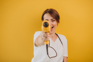 Woman with electric drill on yellow background
