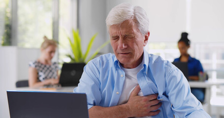 Senior businessman having heart attack in office