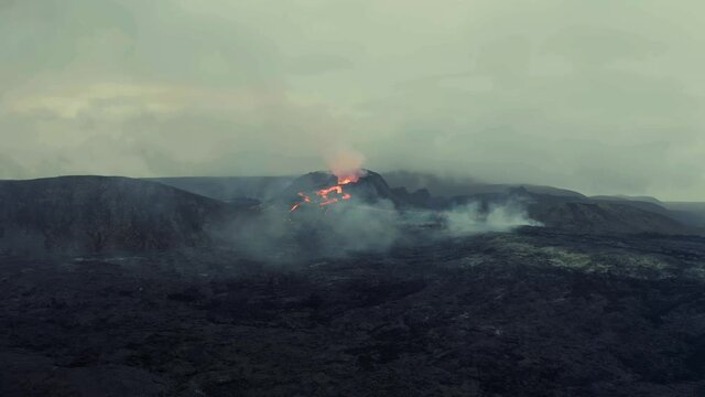 Drone shot towards magma fields and erupting craters in gloomy Iceland - approaching, Aerial view	
