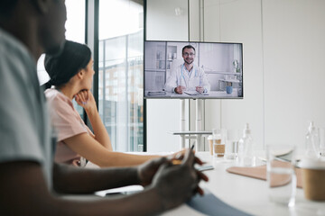 Portrait of male doctor on screen speaking to group of colleagues during medical conference, copy space