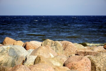 Fototapeta na wymiar A close up of a rock next to water. Stone beach. Gulf of Finland. Blue water. Sea. High quality photo
