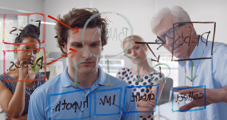 Happy creative team looking at chart on office glass board