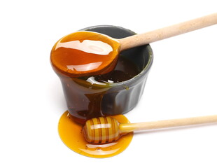 Honey puddle with ceramic bowl, wooden spoon and dipper isolated on white background